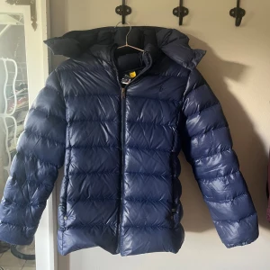 Mörkblå dunjacka Polo Ralph Lauren - Säljer en mörkblå dunjacka från Polo Ralph Lauren. Jätte fint skick.