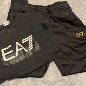 Svarta mjukisbyxor från Emporio Armani och sweatshirt  - Svarta mjukisbyxor från Emporio Armani EA7 med elastisk midja och dragsko. Byxorna har fickor på sidorna och en gul EA7-logga på vänster ben. Perfekta för en avslappnad och sportig stil. Sedan en vanlig sweatshirt. Ok skick, byxorna M tröjan S 
