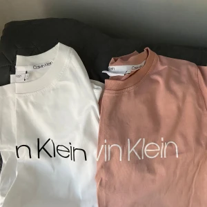 Calvin Klein t-shirt i vitt och rosa - Två snygga t-shirts från Calvin Klein, en i vit med svart logga och en i ljusrosa med vit logga.  Nyskick, bara använda en gång. Inga fläckar, noppor eller slitage 💫 Nypris ca 400–500 kr, säljer båda för 250💕