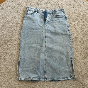 Ljusblå jeanskjol från Lindex - Ljusblå jeanskjol från Lindex. Kjolen är rak i modellen och går ner till knäna. Perfekt för dig som gillar en enkel denimlook.