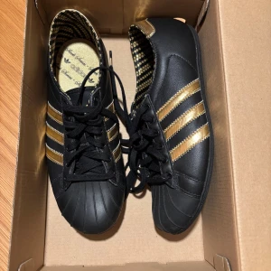 Adidas Sleek Black & Gold Limited Edition (2008)  - Snygga och ovanliga Adidas Sleek i svart med gulddetaljer. Släpptes runt 2008 som en del av Adicolor-serien. Helt oanvända aldrig tagna ut lådan. Modellnummer 404496. Storlek: 36⅔ EU (UK 4 / US 5½ )