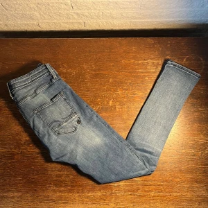 Slim Glenn jeans från Jack & Jones - W32 L34. Slim Glenn jeans från Jack & Jones i klassisk blå tvätt. Modellen har smal passform, fem fickor och subtila slitningar för en avslappnad look. Tillverkade i mjukt bomullsmaterial med stretch för extra komfort.