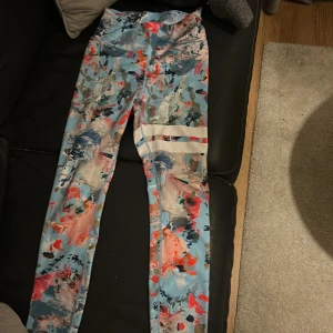Färgglada leggings med abstrakt mönster - Säljer ett par snygga leggings med abstrakt mönster i blått, rosa, orange och vitt. Perfekta för träning. Från stronger