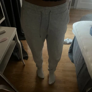 Grå mjukisbyxor med snörning XS - Säljer ett par ljusgrå mjukisbyxor i storlek XS. Byxorna har resår i midjan, snörning och muddar vid bensluten. Perfekta för chill dagar och riktigt sköna tack vare mjukt bomullsmaterial.