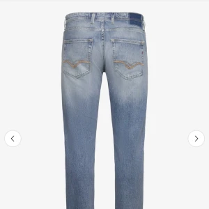 Replay ljusblå jeans med raka ben - Säljer ett par ljusblå jeans från Replay med klassisk femficksdesign och snygga slitningar. Jeansen har raka ben, normal passform och subtila detaljer på bakfickorna. Perfekta för en avslappnad och trendig look.