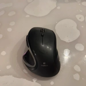 Logitech Performance MX - Ergonomisk trådlös mus från Logitech, modell Performance MX. Flera programmerbara knappar och Darkfield-laser för hög precision. Synligt bruksslitage men i gott skick, fungerar utmärkt för både arbete och spel.