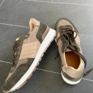 Selected Homme sneakers i beige och grönt  - Snygga sneakers från Selected Homme i storlek 40. Skorna har en beige och grönt färgkombination med mesh och mockadetaljer, samt bruna snören och vit sula. Perfekt för dig som gillar stilrena och jordnära färger. Tillverkade i Portugal.oanvända 