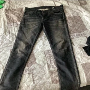 True Religion svarta jeans med broderade fickor - Svarta jeans från True Religion med snygga slitningar och broderade bakfickor med den klassiska bågdesignen. Jeansen har raka ben och normal passform, tillverkade i jeansmaterial med coola detaljer på baksidan av benen och logotyp på insidan.