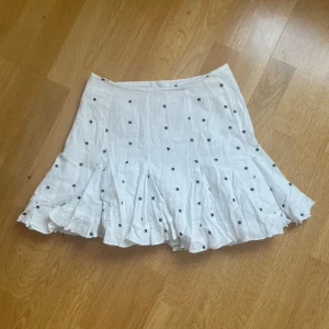 Vit kjol med svarta blommor!! - Vit kjol med broderade svarta blommor på från Zara, köpt i London ⭐️ Använd och har en liten fläck (se bild 4) som nästan inte syns. Det finns en dragkedja på vänster sida. Storlek S