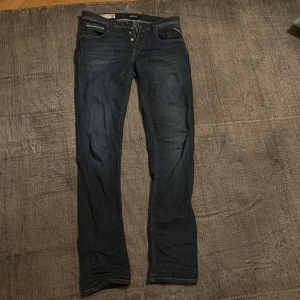 Replay Grover jeans straight fit blå - Säljer ett par mörkblå Replay Grover jeans i straight fit. Klassisk femficksmodell med knappgylf och snygga slitningar. Jeansen är tillverkade i jeansmaterial och har en stilren look som passar till det mesta.