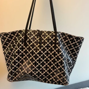 By Malene Birger väska - En äkta väska från By Malene Birger i svart och vit. Stor och rymlig shoppingväska med ett snyggt grafiskt mönster. Väskan har långa svarta axelband. Om ni är intresserade får ni jätte gärna skriva privat så kan jag skicka fler bilder. Den är välanvänd och har mycket defekter. Slitage finns vid t.ex. handtag, hörn, på trycket, invändigt mm. Pris kan diskuteras. 