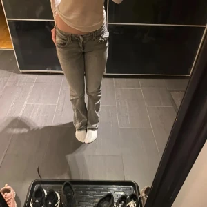 Grå jeans från Gina Tricot, stl 158 - Snygga grå jeans från Gina Tricot i storlek 158. Modellen har låg midja, raka ben och coola detaljer med fickor och knappar bak. Jeansen är i klassisk denim med en tvättad look som ger en trendig vibe.