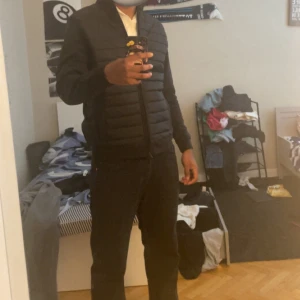 Svart cardigan från dressman -   Jackan har ståkrage, dragkedja hela vägen och två sidofickor. Perfekt för dig som vill ha en clean och stilren look under höst och vinter.