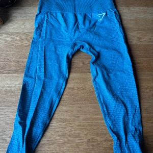 Blå träningstights från Gymshark - Snygga blå träningstights från Gymshark med seamless design. De har diskreta mönster längs benen och en bred ribbad linning som sitter skönt. Perfekta för träning eller chill. Stretchigt material som formar sig efter kroppen och aldrig använda!💙