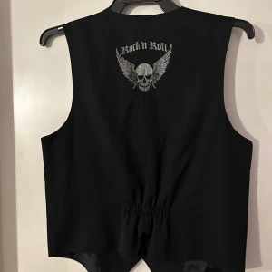 Väst med döskalletryck bak. Storlek 40 - Helt ny fodrad väst. Tufft tryck i silver. Storlek 40.