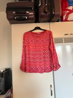 Odd molly topp - Säljer en otroligt vacker topp i en mörkare korall färg. Den har ett fint detaljerat mönster i orange, vitt och rosa.  Från märket Odd Molly. Storlek 2 som enligt deras storleksguide motsvarar en M. Mycket fint skick, jag hittar inga synliga anmärkningar eller defekter. 