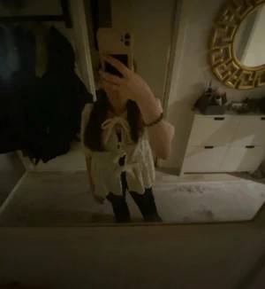 Vit blus med knyt och volang - Säljer en söt vit blus med knyt framtill och volangdetaljer. Blusen har korta ärmar och en luftig passform som ger en chill vibe. Perfekt för dig som gillar romantiska och trendiga plagg med extra detaljer.