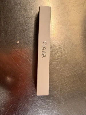 CAIA Perfect Pout Lip Primer - Säljer en CAIA Perfect Pout Lip Primer i en stilren ljusbeige förpackning. Produkten är designad för att ge en jämn bas till läpparna och förbättra hållbarheten på ditt läppsmink. Perfekt för dig som vill ha extra snygga och definierade läppar.