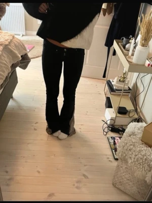 Svarta bootcut jeans med leoparddetalj - Säljer ett par svarta jeans med bootcut passform och snygg leopardmönstrad detalj på insidan av bensluten. Byxorna har normal midja och klassisk femficksdesign. Perfekt för dig som vill sticka ut med en unik twist på dina jeans.
