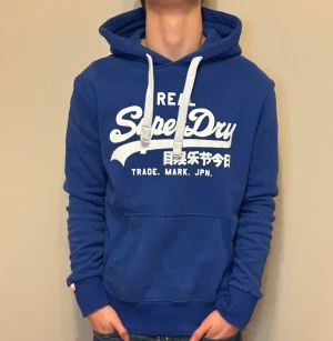 Superdry Hoodie Blå - Superdry Hoodie Blå - Pris: 549 kr - Storlek: M - Defekt: Logotyp Sprucken, annars i fantastisk skick. - Först till Kvarn!