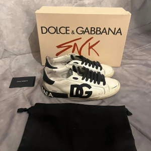 Dolce & Gabbana sneakers - Tja! Vi säljer ett par vita Dolce & Gabbana sneakers med svart DG-logga på sidan och svart text på hälen. Skorna är i ett mycket bra skick! Hör av er vid frågor och funderingar!😁