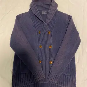 Säljer denna Kashmir cardiganen från polo i storlek XS men passar också S | skick 8/10. Den har en dubbelknäppt design med bruna knappar och två praktiska fickor framtill. Perfekt för kyliga höst- och vinterdagar. Koftan har en ribbad krage och muddar som ger en stilren look.