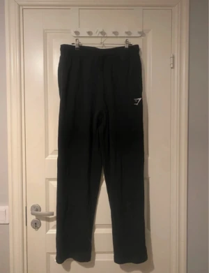 Straight leg mjukisbyxor - Säljer dessa mjukisbyxor från gymstark i modellen ” Gymshark Crest Straight Leg Joggers - Black ” . Använd fåtal gånger, perfekt att ha på gymmet eller hemma. Passar även M skulle jag säga. Passar mig bra i längden som är 168cm.  Material 80% Cotton, 20% Polyester
