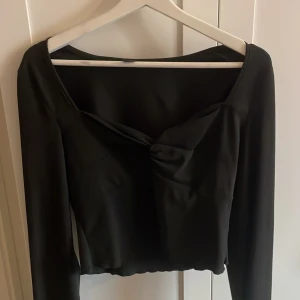 Svart långärmad topp - Säljer en svart långärmad topp med omlottkänsla och twistad detalj framtill. Liknar ginas knyt tröjor. aldrig använd, bara hängt i garderoben 
