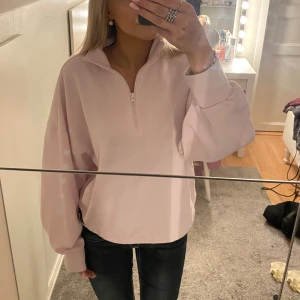 Ljusrosa Adidas half zip sweatshirt - Superfin ljusrosa sweatshirt från Adidas med oversized passform och halv dragkedja. Tröjan har långa ärmar, hög krage och stor vit Adidas-logga på ryggen. Passar S fast storleken är M