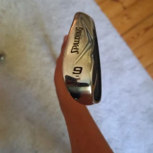 Spalding SP99 9 Iron - Spalding SP99 9-järn i rostfritt stål. Klubban är i gott skick med endast mindre bruksspår på klubbhuvudet. Perfekt för både nybörjare och erfarna golfare som söker en pålitlig järnklubba. Greppet är intakt och klubban är redo för spel.