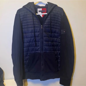 Tommy Hilfiger Cardigan - Snygg mörkblå cardigan från Tommy Hilfiger med quiltad framsida och huva. Jackan har dragkedja, två fickor fram och diskret logga på ärmen. Perfekt för dig som gillar stilren look. Storleken är XL men passar L. Nypris 2300 mitt pris 799✅
