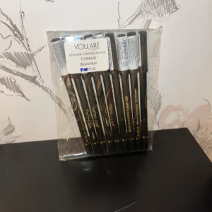 Svart eyelinerpenna från Vollare - Säljer ett 9-pack svarta eyelinerpennor från Vollare Cosmetics. Pennorna har en klassisk trädesign med svart hylsa och guldtext. Perfekt för att skapa skarpa och intensiva linjer runt ögonen. Färgen är djup svart och pennan är lätt att vässa.