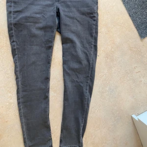 Mörkgrå skinny jeans från Divided - Mörkgrå skinny jeans från Divided med klassisk femficksdesign och dragkedjegylf. Jeansen har smal passform och är tillverkade i stretchigt bomullsmaterial för en bekväm känsla. Perfekta för dig som gillar en stilren och enkel look. Man kan göra om de till jeanskjol eller shorts ifall man inte gillar skinny jeans. 