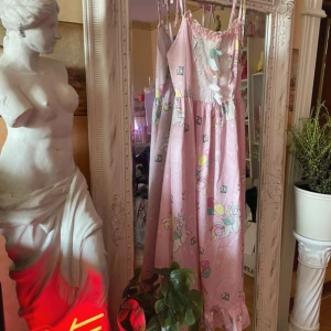 Dress No°1 - Supersöt rosa långklänning med gulligt enhörningsmönster, ballonger och kronor. Klänningen har spets upptill, smala axelband och volangkant nertill. Dekorerad med pastellfärgade rosetter framtill. Perfekt för dig som älskar pastell och kawaii-stil!