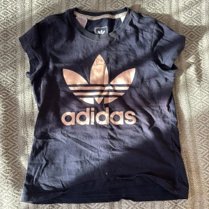 Mörkblå Adidas t-shirt med logga - Snygg mörkblå t-shirt från Adidas med den klassiska stora loggan i vitt framtill. Modellen är kortärmad och har en normal passform. Perfekt för dig som gillar sportiga och stilrena plagg. Är i storlek 9/10 år US men jag som har ca XS har på mig den som en helt vanlig tshirt💕