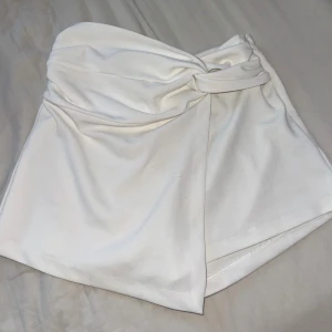 Vit shorts/kjol från Zara - Vit shortskjol från Zara med dragkedja på sidan. Storlek M men sitter som S.