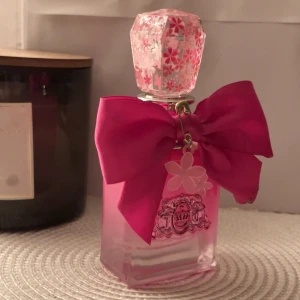 Juicy Couture Petals Please 50ml - Snygg parfymflaska från Juicy Couture med rosa detaljer, stor rosett och blomma som hänge. Endast använd fåtal gånger, fick i present men doften passade inte mig därav säljer jag den vidare. ☺️ 