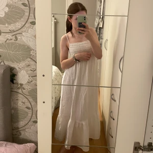 Vit långklänning  - Superfin vit långklänning med smock upptill och tunna axelband ( Ellia). Från Lager 157 i storlek Xs. Helt ny och tagen sitter kvar då jag glömt att retunera. Ordinarie 200 kr