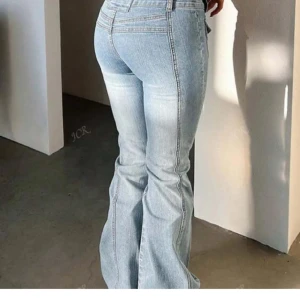 Ljusblå bootcut jeans - Säljer ett par ljusblå jeans med bootcut och låg midja. Jeansen har snygga framfickor med lock och dubbla knappar i midjan. De är tillverkade i klassiskt denimtyg och har en riktigt trendig 2000-talsvibe. Perfekta för dig som gillar en avslappnad men ändå cool stil.(den är från shien!)