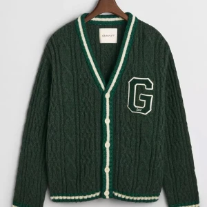 Grön stickad kofta från Gant - Mörkgrön stickad kofta från Gant med vita och gröna ränder längs knäppningen och nederkanten. Stort G-broderi på bröstet, v-ringad och med vita knappar. Perfekt för lager-på-lager och snygg till skjorta. Helt oanvänd och med etiketter kvar Inköpt på johnells och kvitto finns. Nypris 2699kr