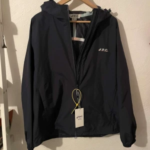 A.P.C. Windbreaker - Vi säljer denna sjukt snygga mörkblå, hyrdrofobiska windbreaker från Asics x A.P.C. Storlek M och är i nyskick med tags kvar på! Skriv ifall du har några funderingar!                                   Mvh Garçon Studios
