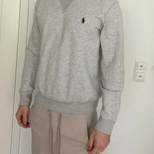 Grå sweatshirt från Polo Ralph Lauren - Snygg ljusgrå sweatshirt från Polo Ralph Lauren med klassisk broderad logga på bröstet. Tröjan har ribbade muddar vid ärmslut och midja samt en relaxed passform. Har använd lite och är mycket bra skick! Om du har mer frågor, skicka gärna ett meddelande till mig!