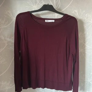 Vinröd långärmad tröja från Zara - En vinröd långärmad tröja från Zara med bred och rund halsringning. Tröjan är tunnstickad och har en enkel, klassisk design som passar perfekt till lager-på-lager. Skönt material till varmare kvällar! Ej använd!!!!Den är väldigt liten i storleken, passar garanterat allt ifrån S-L beroende på hur man vill att passformen ska vara. 