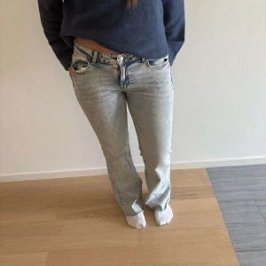 Ljusblå bootcut jeans - Snygga ljusblå jeans med bootcut passform och låg midja. Jeansen har klassisk femficksdesign, dragkedja och knapp framtill samt slitna detaljer vid benslut. Perfekta för en avslappnad och trendig look.