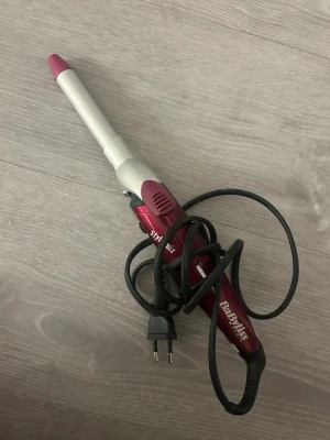 Locktång BaByliss röd/silver - Locktång från BaByliss i snygg röd och silver design med rosa topp. Perfekt för att fixa snygga lockar snabbt. Utrustad med sladd och EU-kontakt. Smidig storlek och lätt att använda för både långa och korta hår.