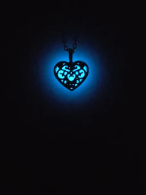 Handgjort halsband som lyser i mörkret! 💙 - Unikt hantverk! Ett mönstrat hjärta i silverton där jag själv fyllt i detaljerna för hand. ​✨ I ljus: Stilren vit färg. 🌙 I mörker: Lyser magiskt blått efter laddning med sol/UV-ljus. ​Materialet är av högsta kvalitet, giftfritt och lyser upp till 12h. Kedja i rostfritt stål, 45 lång. Helt nytt!