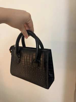 Svart handväska  - Säljer denna helt nya väska. Band finns med så kan användas som axelremsväska 