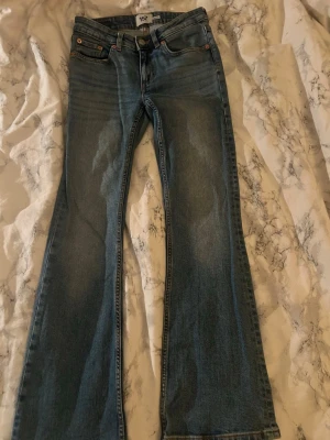 Blå bootcut jeans från 157, XS short - Snygga blå bootcut jeans från 157 i storlek XS short. Jeansen har låg midja.Tillverkade i jeansmaterial med lätt tvättad look och dragkedja framtill. Perfekta för dig som gillar en retro vibe och vill ha ett par riktigt schyssta jeans.