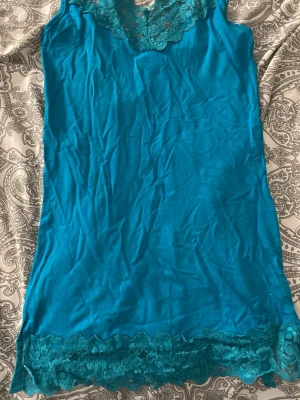 Turkos spetslinnetopp Gina Tricot - Säljer en turkos linnetopp från Gina Tricot i storlek S. Toppen har bred spetskant både upptill och nedtill samt smala axelband. Materialet är mjukt och stretchigt, perfekt för sommardagar eller som layering-piece. Enkel men ändå detaljerad med spets.