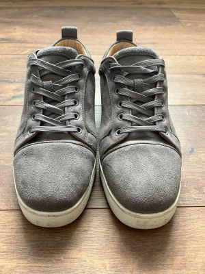 Grå mockasneakers från Christian Louboutin - Säljer mina Christian Louboutin då de inte används längre, skon funkar bra till nästan vad som helst. De ser knappt använda utan förutom på sulan där det har blivit lite repigt. Har du frågor så ställ gärna!😁